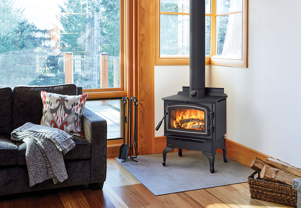 A cozy living room with a burning wood stove and a dark sofa.